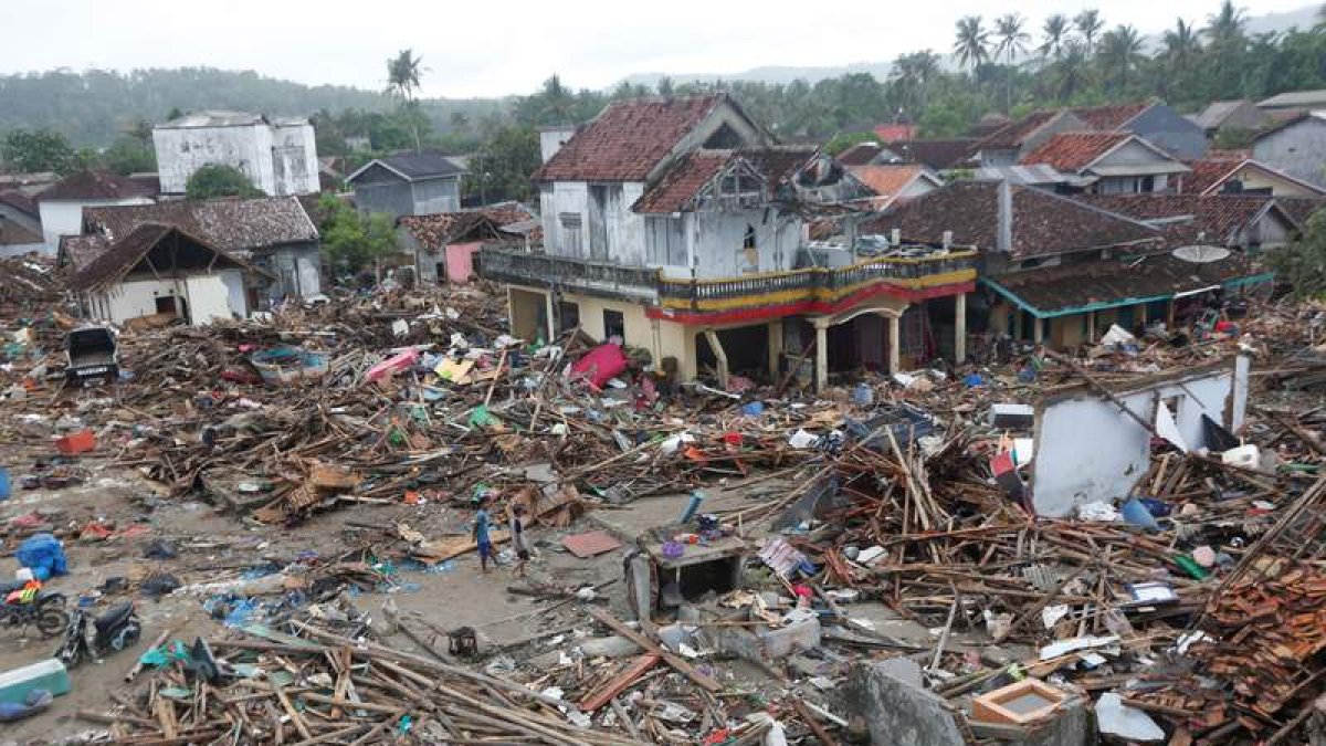 Los residentes caminan entre los escombros en el área devastada por el tsunami. ADI WEDA