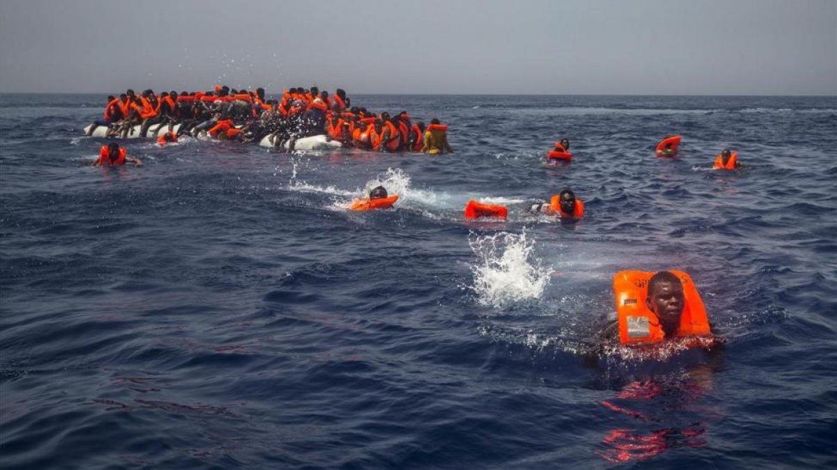 Un grupo de emigrantes y refugiados africanos intentan alcanzar a nado el barco de la oenegé Proactiva Open Arms.