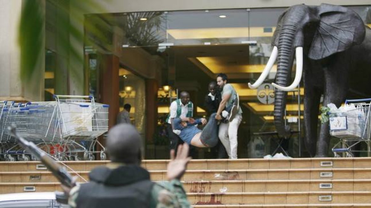 Dos personas ayudan a salir a uno de los heridos en el tiroteo en el centro comercial Westgate, en Nairobi.