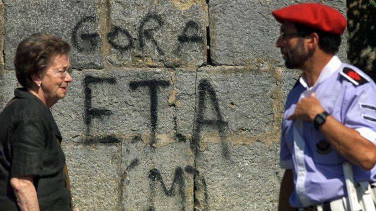Una mujer y un erzaina pasan ante una pintada en favor de ETA, en una imagen de archivo.