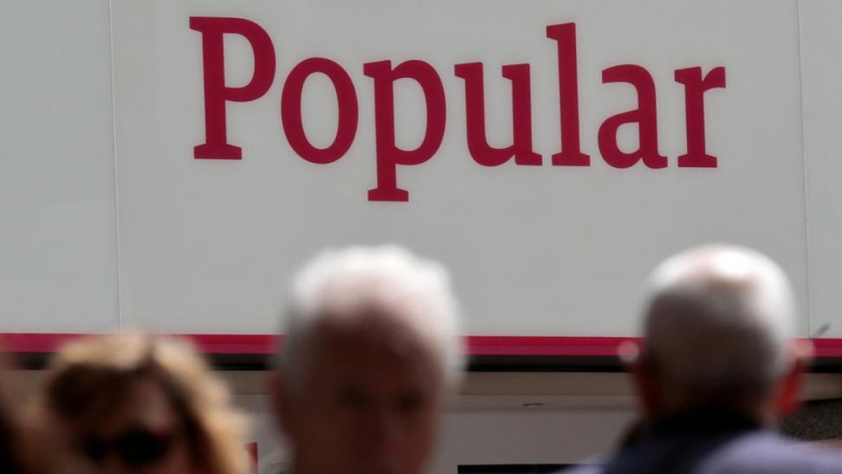 Personas pasando por delante de unas oficinas del Banco Popular.