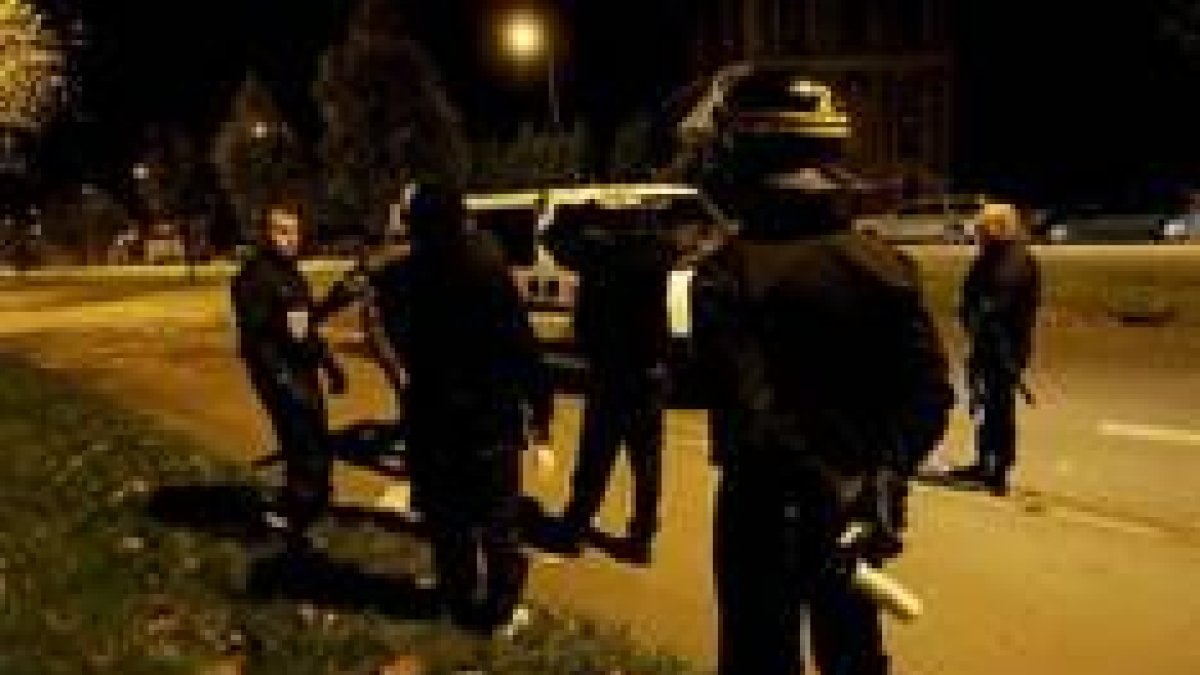 Los policías interrogan a unos jóvenes después de que varios coches fueran incendiados por vándalos