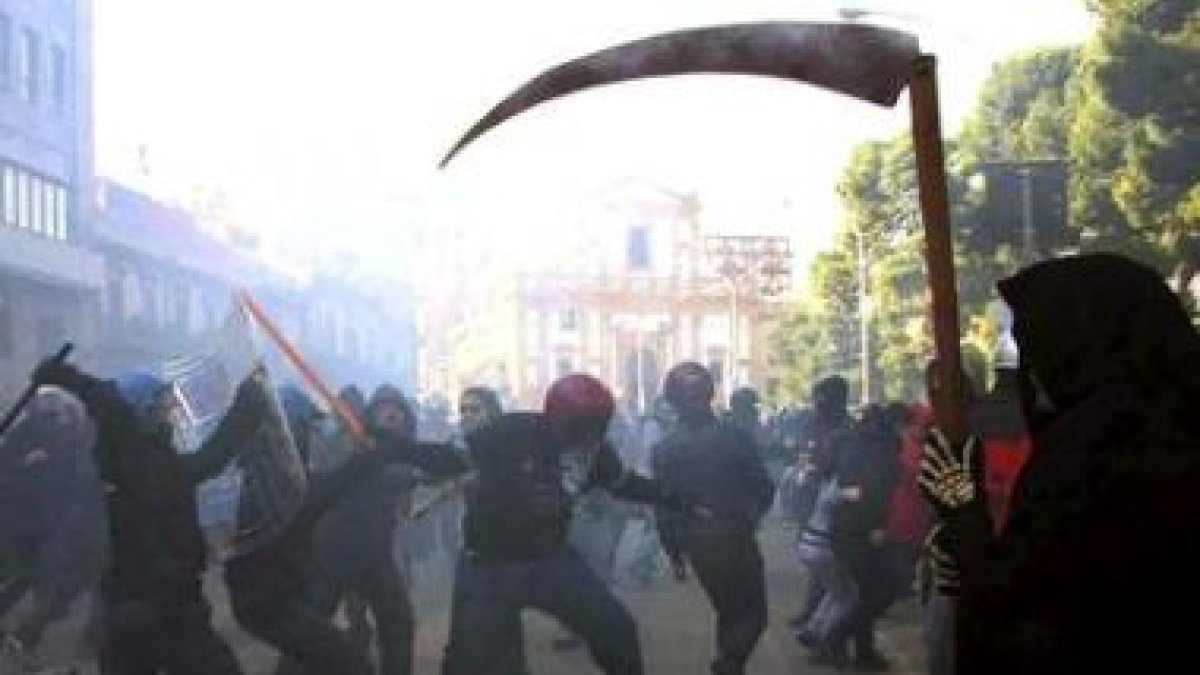 Un policía antidisturbios golpea a un manifestante.