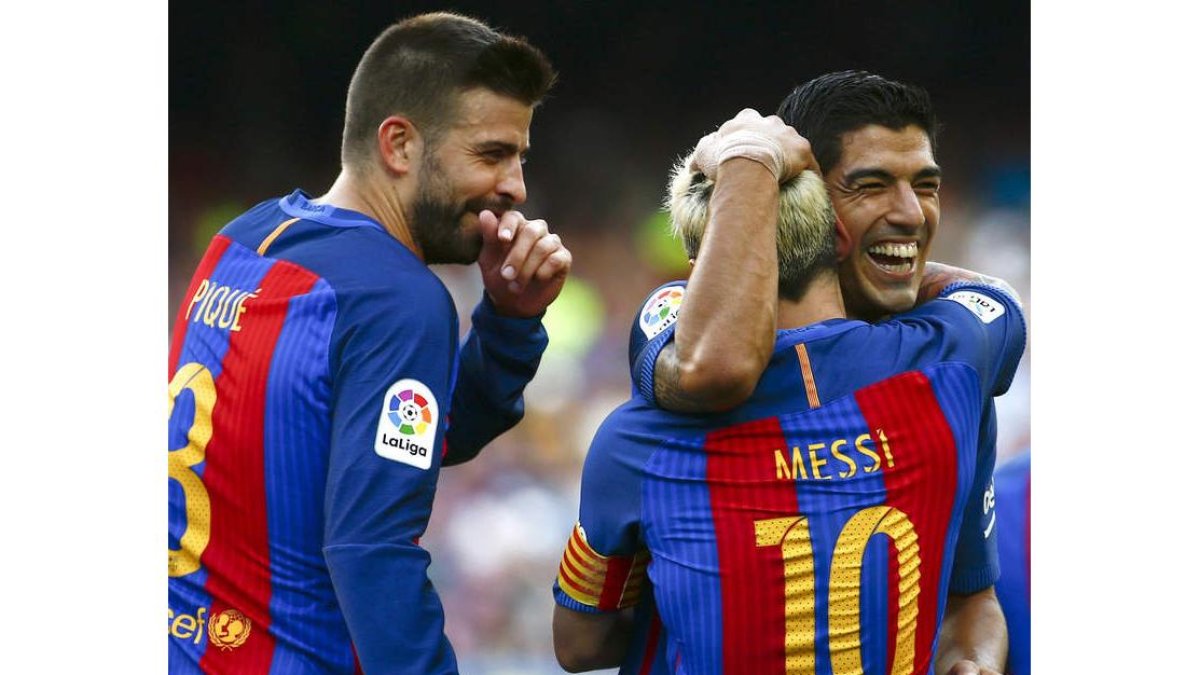 Leo Messi celebra junto a Luis Suárez, ante la mirada de Gerard Piqué, el quinto gol del equipo en el partido ante el Betis. QUIQUE GARCÍA