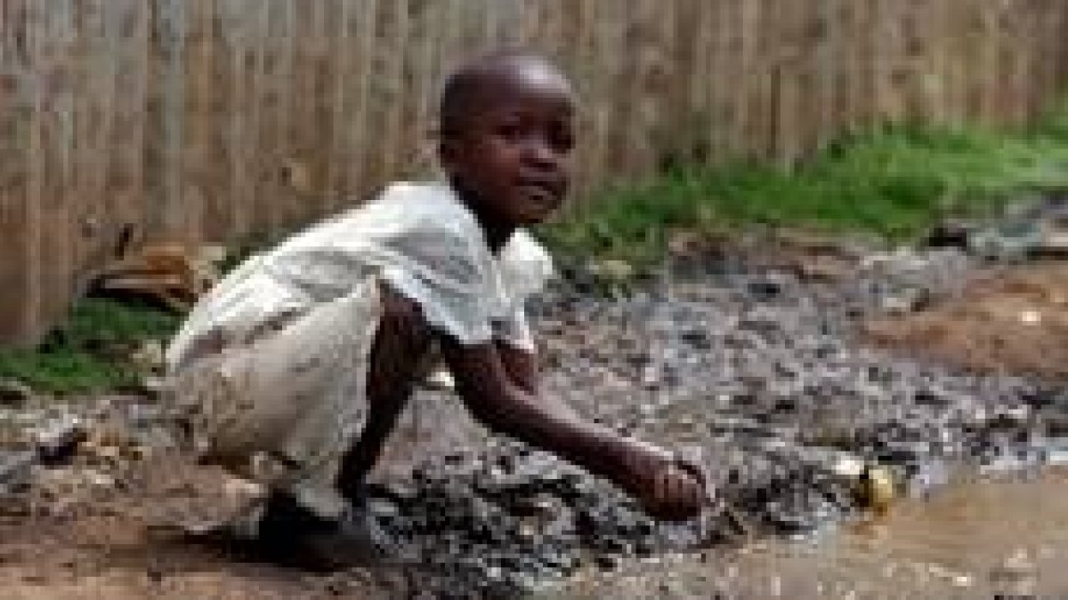 Una niña se lava las manos en un charco, una de las principales fuentes de enfermedades