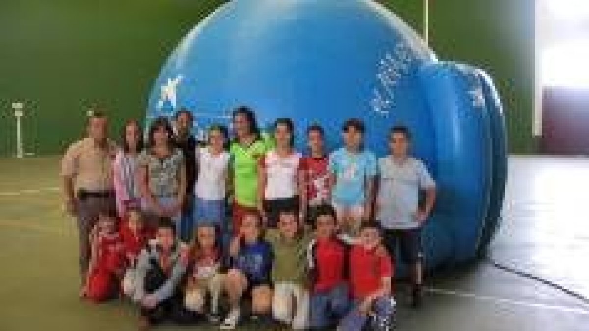 Un grupo de niños posa con su profesor antes de entrar al planetario viajero