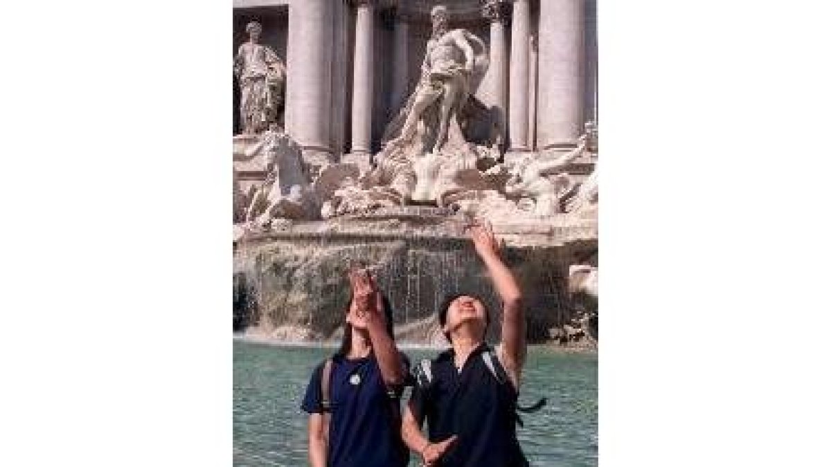 Dos turistas asiáticos arrojan monedas a la Fontana de Trevi como manda la tradición