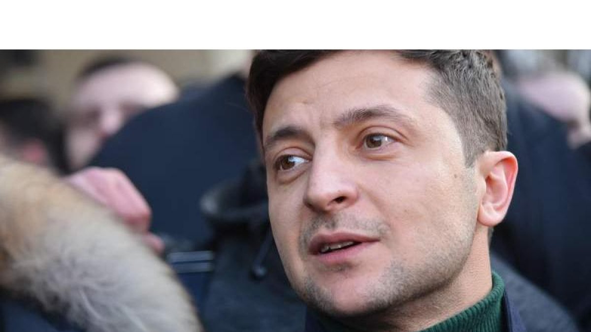 Zelenski habla con ciudadanos y medios de comunicación. Abajo, una voluntaria quita el agua del techo de una carpa de la candidata a la presidencia ucraniana, Yulia Timoshenko, este martes en Kiev.