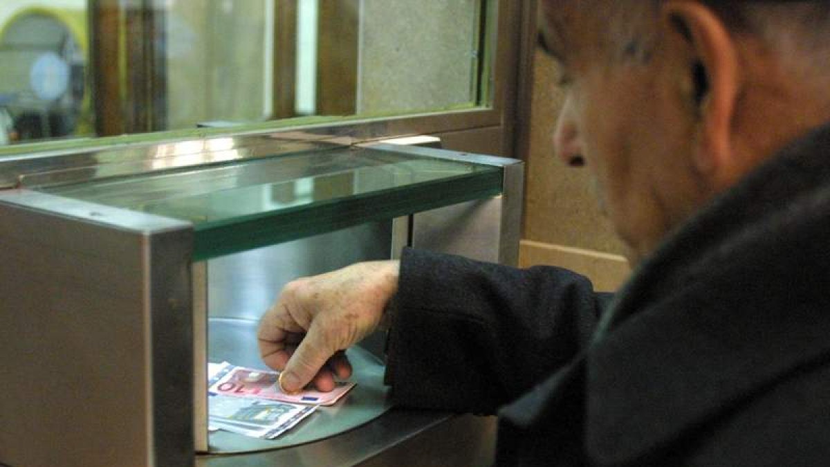 Un hombre ingresa dinero en la ventanilla de una entidad bancaria.