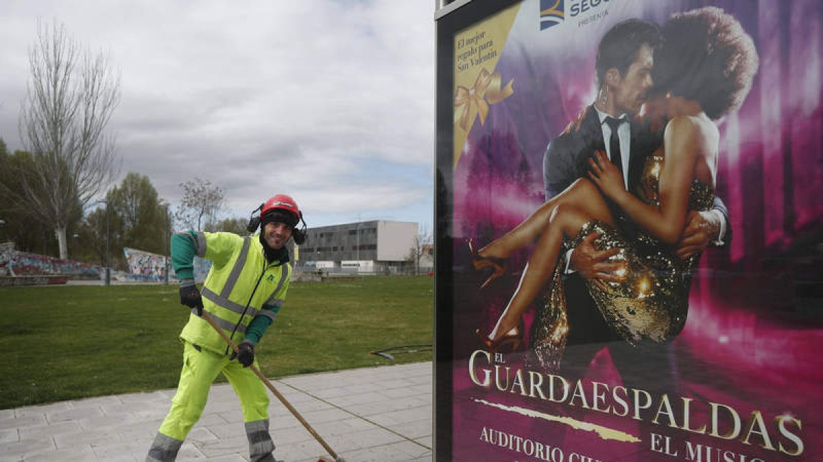 Un barrendero de León durante el confinamiento por la pandemia, con el cartel del musical que llegará en junio a León. JESÚIS F. SALVADORES