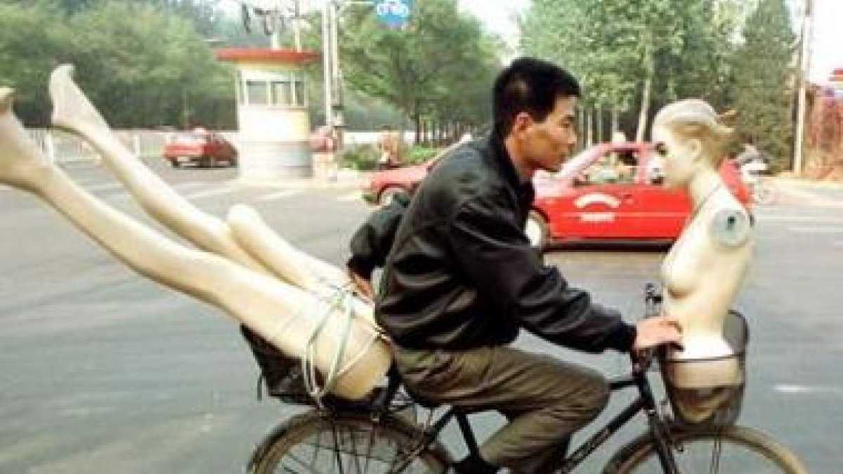 Un joven atraviesa las calles de Beijiing con un maniquí en su bicicleta, en una imagen de archivo.