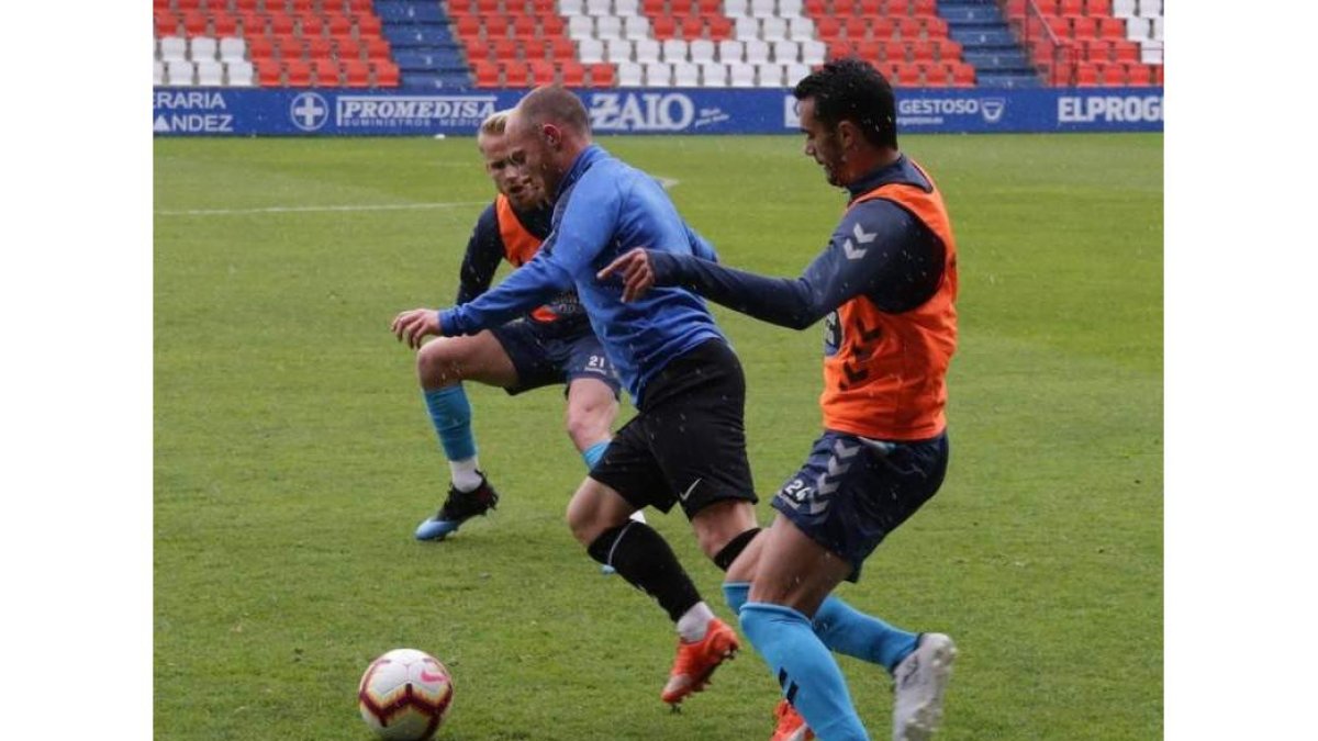 Isi se va entre dos jugadores del Lugo con la lluvia como telón de fondo en el partidillo jugado ayer en el Anxo Carro. CD LUGO