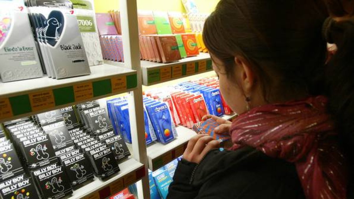 Una chica, frente a un estante repleto de preservativos en una tienda especializada de Barcelona.