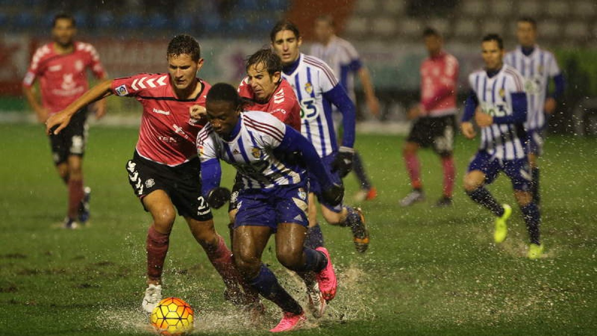 Melero es entrado por un adversario. Jugar en un campo encharcado se hizo difícil.