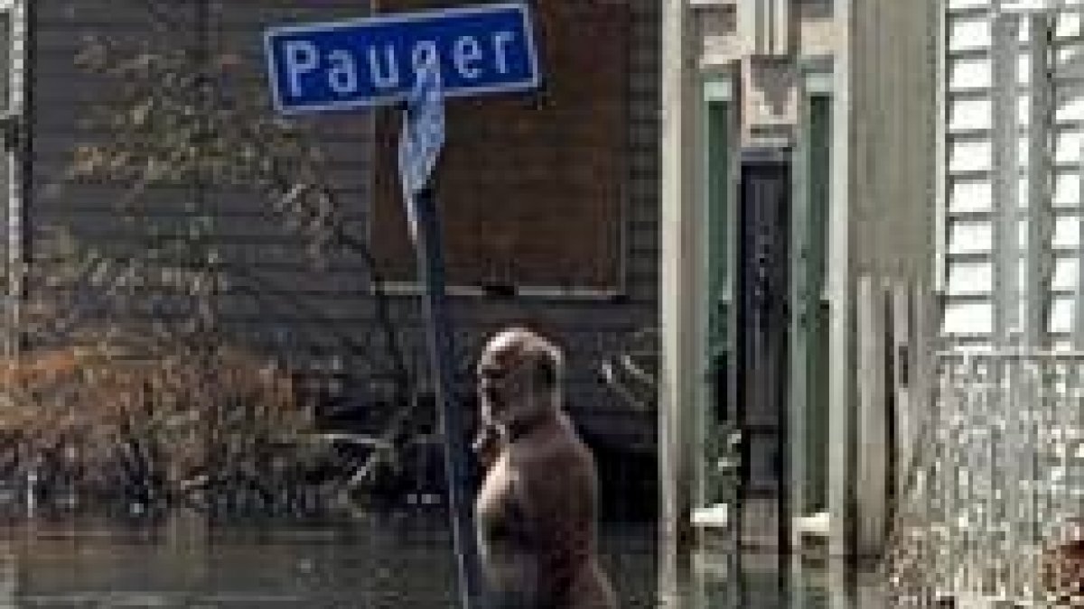 Un hombre que rechazó abandonar la ciudad camina a través de una calle inundada