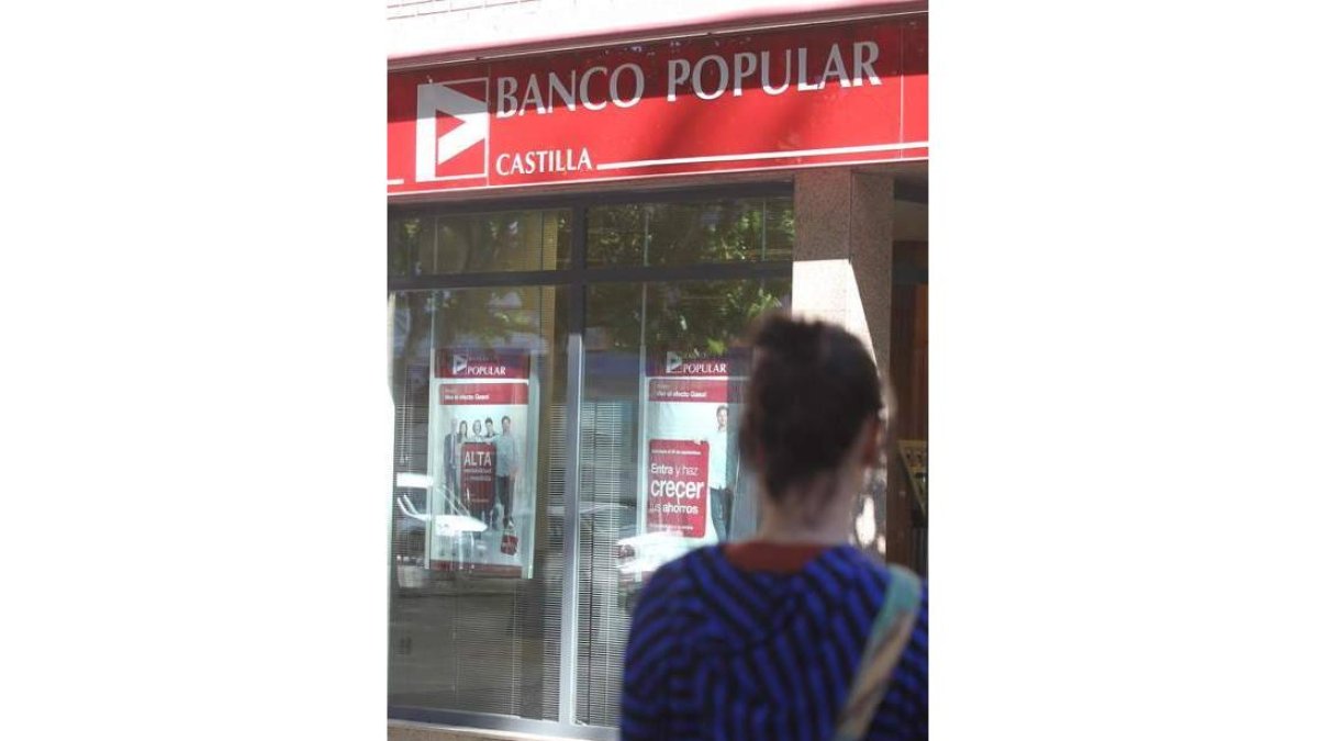 La joven Laura, de espaldas, ante la sucursal bancaria.