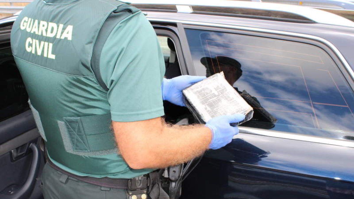 Un guardia civil porta el paquete con la cocaína interceptada en un vehículo en Trabadelo. DL