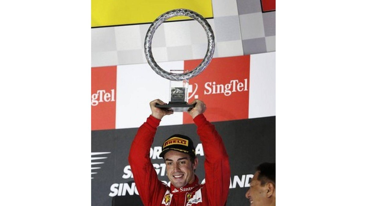 Fernando Alonso levanta su trofeo en el podio, tras lograr el tercer puesto en Singapur, este domingo.