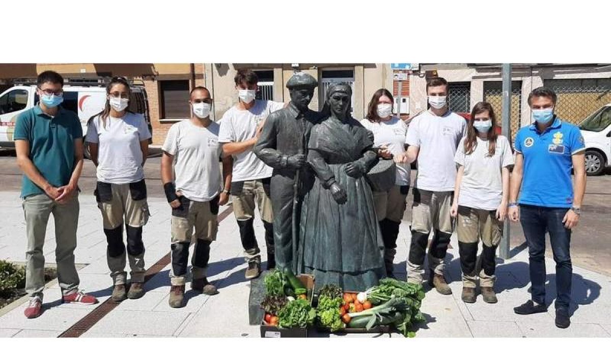 Los representantes municipales con los alumnos del taller junto a la escultura de los hortelanos. DL