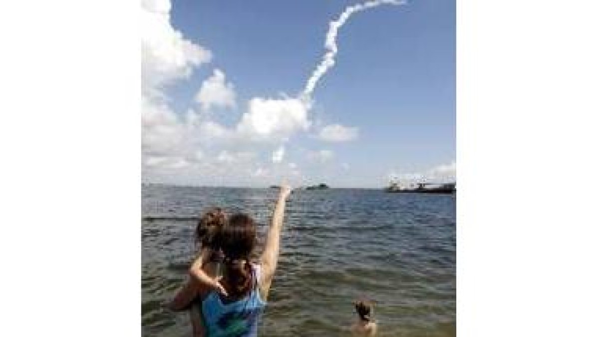 Una mujer muestra a su hijo la estela de humo dejada por el «Atlantis»