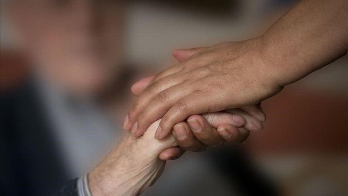 Un enfermo de Alzhéimer da la mano a un familiar.