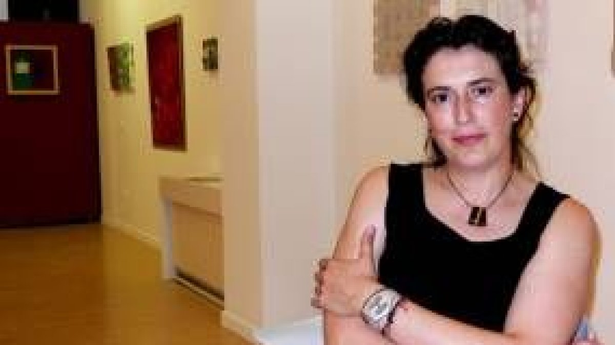 La pintora leonesa Cristina Ibáñez posa con algunas de las obras que expone en Ármaga