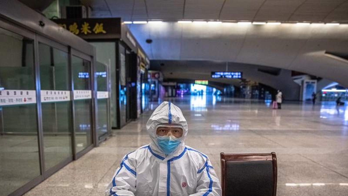 Un operario de trenes con un traje protector espera la llegada de viajeros en Wuhan.