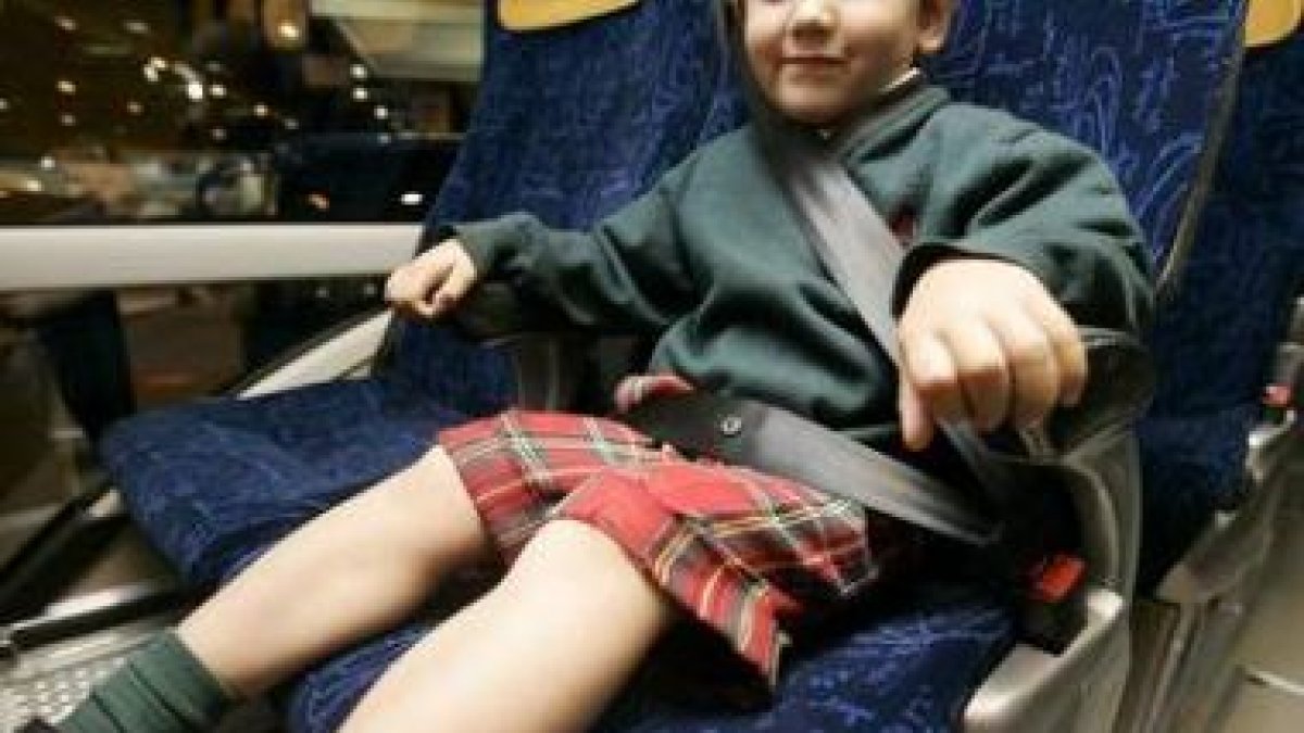 Un niño viaja en un atubús con el cinturón de seguridad puesto.