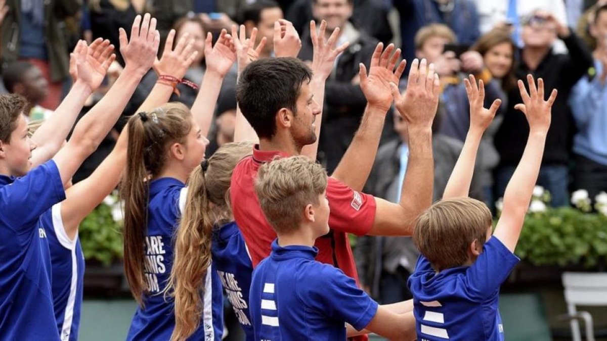 Djokovic celebra con los recogepelotas su victoria en París.