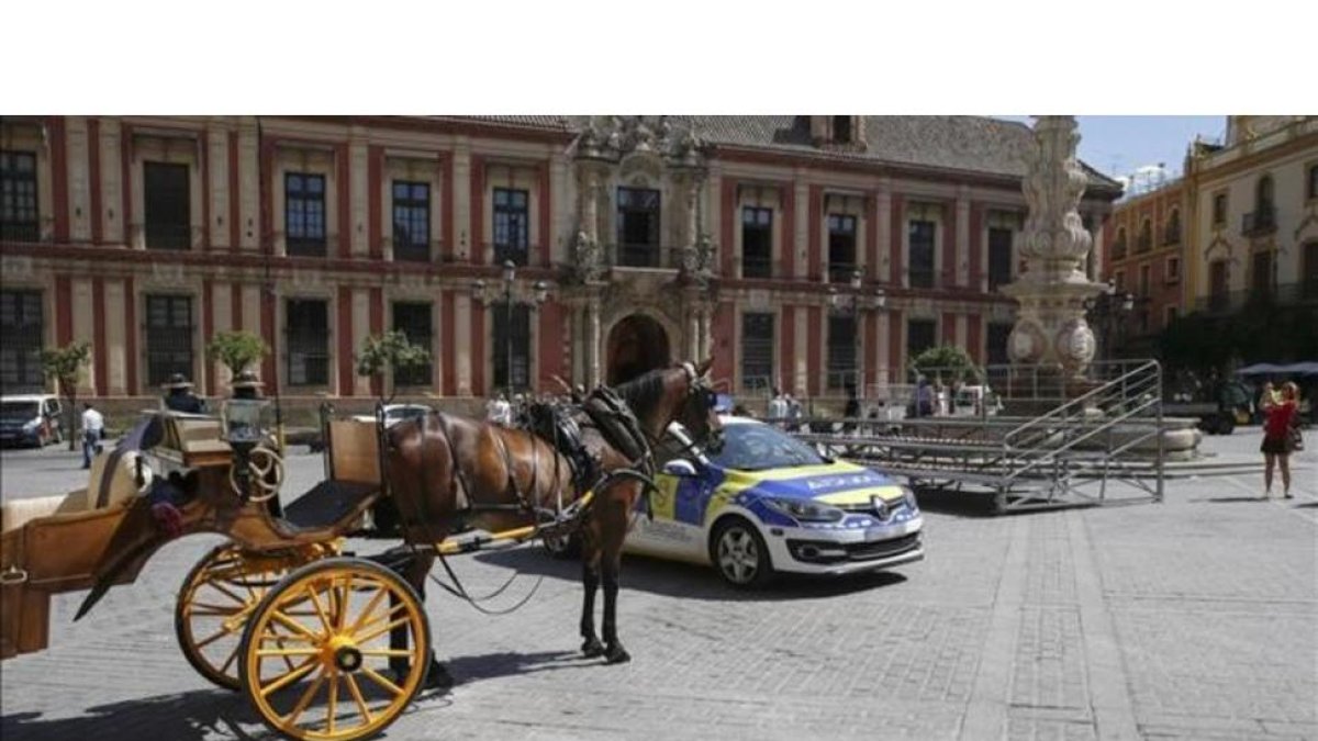 Un coche de caballos y una patrulla policial junto a una de las tribunas, en la Plaza de la Virgen de los Reyes, que estaban preparadas para la visita del presidente de EEUU Barack Obama a Sevilla, que finalmente ha sido cancelada