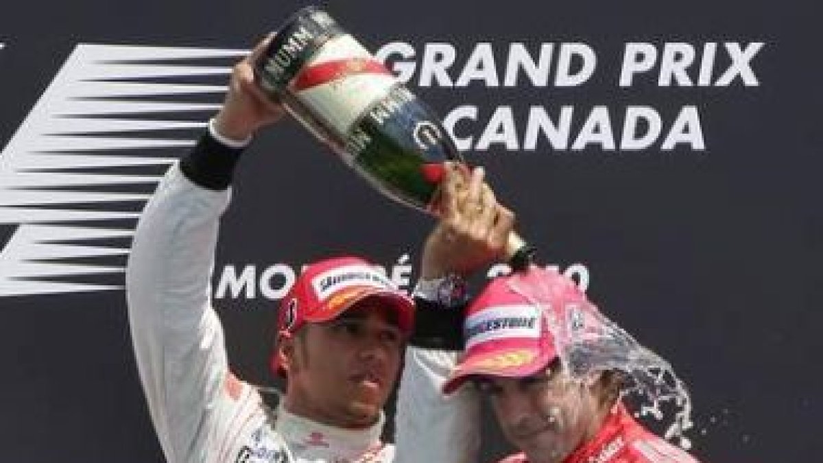 El piloto británico Lewis Hamilton, a la izquierda, moja con champán al piloto español Fernando Alon