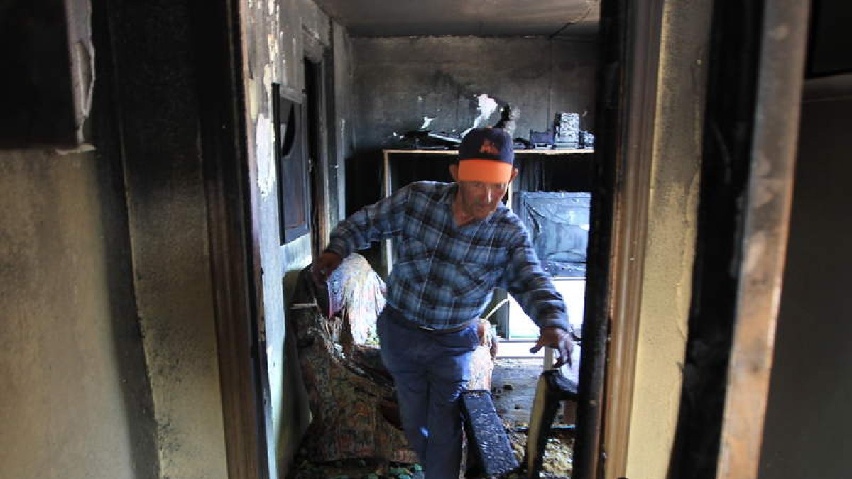 El padre del afectado recorre la vivienda después de que los bomberos sofocaran las llamas.