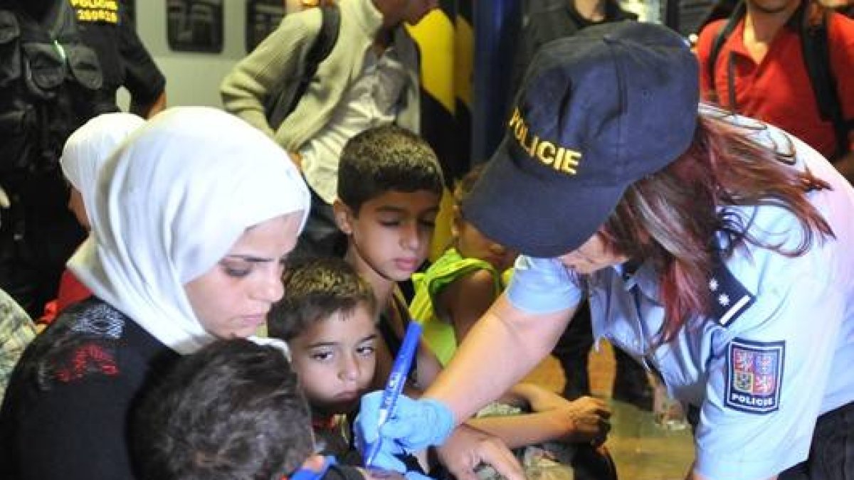 Una agente de policía checa escribe el número en la mano de un niño.