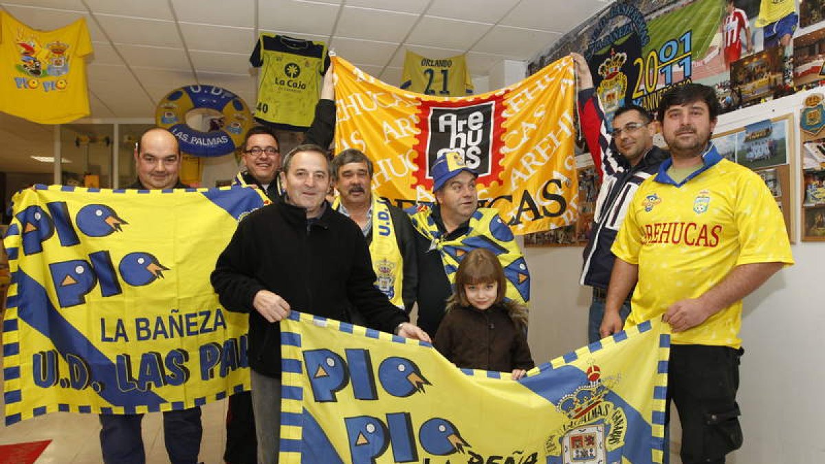 Hermógenes Celada, en el centro con una bufanda de Las Palmas, posa en la sede de la peña con varios aficionados de los 190 que conforman la masa social ‘amarilla’.