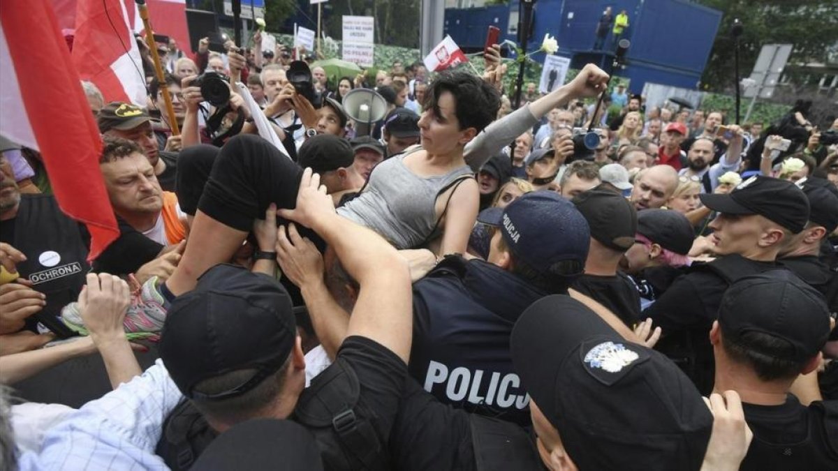 Un grupo de personas intentan romper la barrera formada por la policia durante una protesta en Polonia