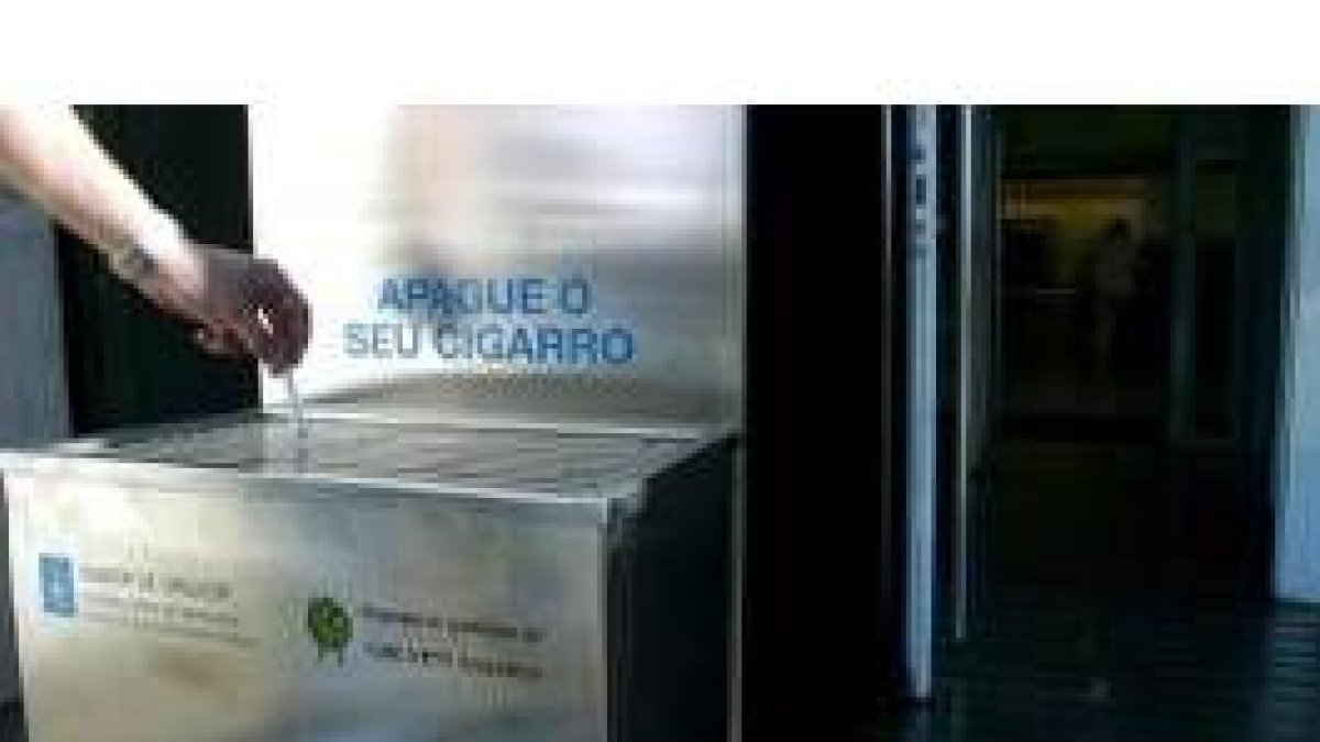 Un fumador apaga su cigarrillo en unos ceniceros instalados por la Xunta