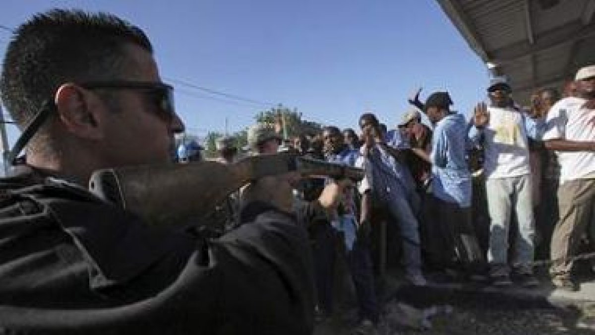Un policía jordano trata de controlar a la multitud que buscaba trabajo en el aeropuerto.