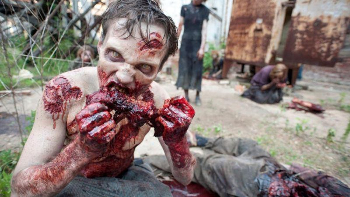 Uno de los zombis de la serie The walking dead, devorando a una de sus víctimas.
