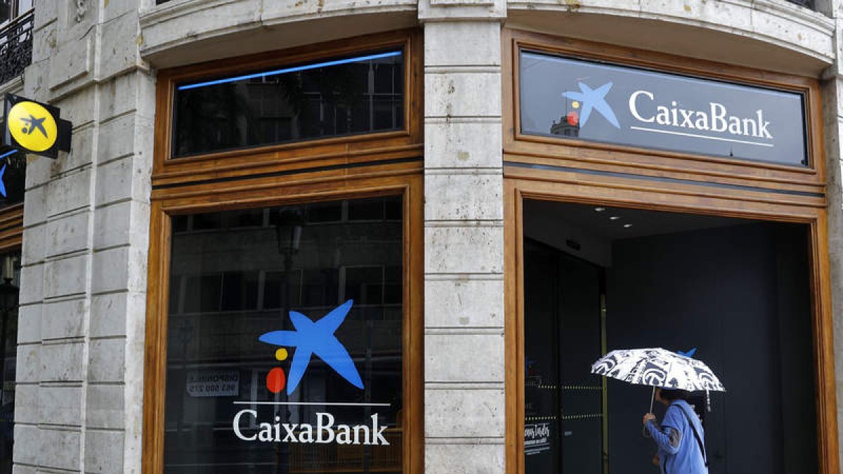 Una mujer observa la sede de Caixa Bank en la plaza del Ayuntamiento de Valencia. MANUEL BRUQUE