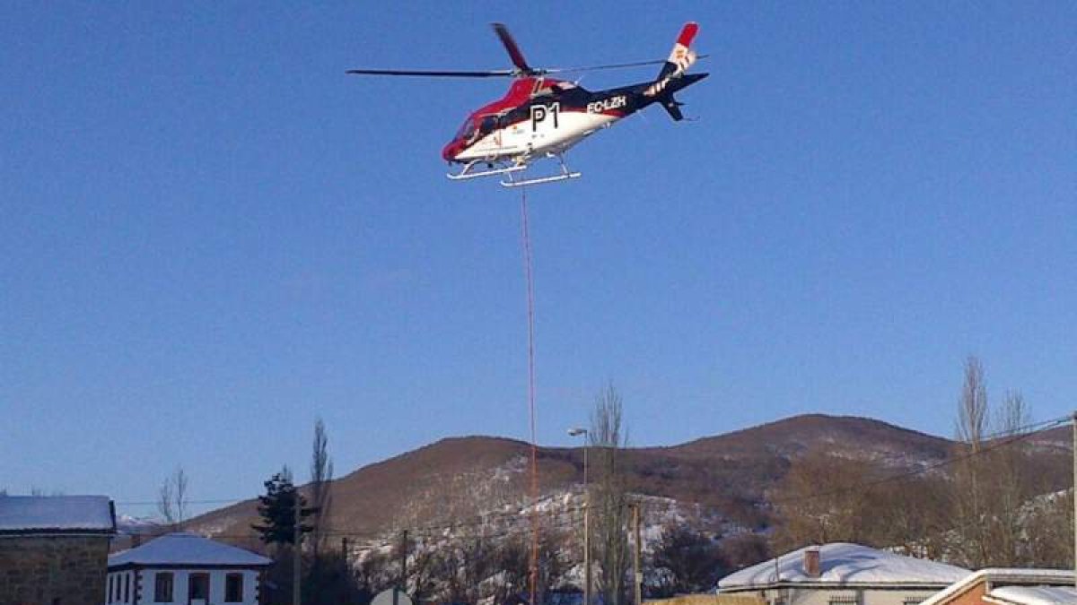 U helicóptero de la Junta carga paja y pienso en la carretera de Prioro para trasladar comida al ganado atrapado por la nieve en Tejerina