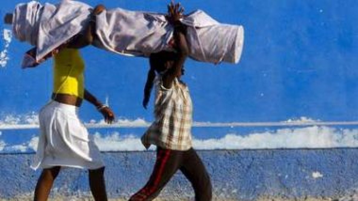 Dos niñas haitianas portan un rollo de tela.