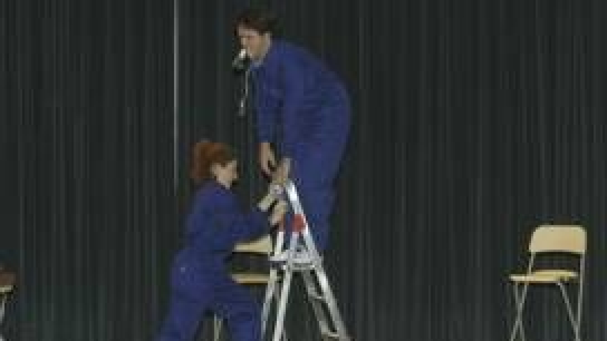 Dos de los actores de la representación teatral se afanan en colocar una bombilla