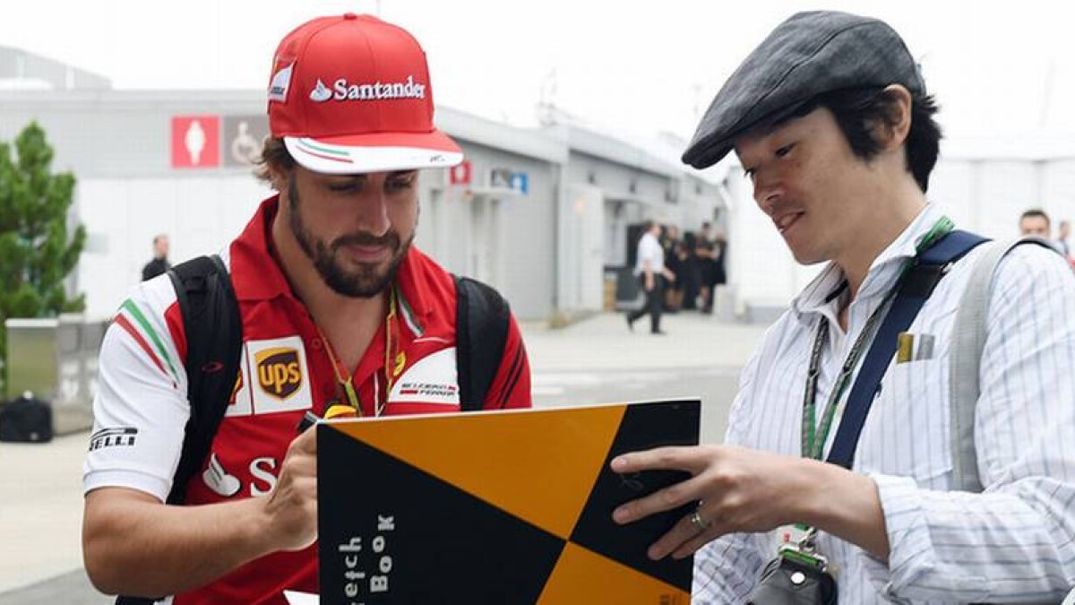 Fernando Alonso firma un autógrafo a un fan en el circuito de Suzuka.