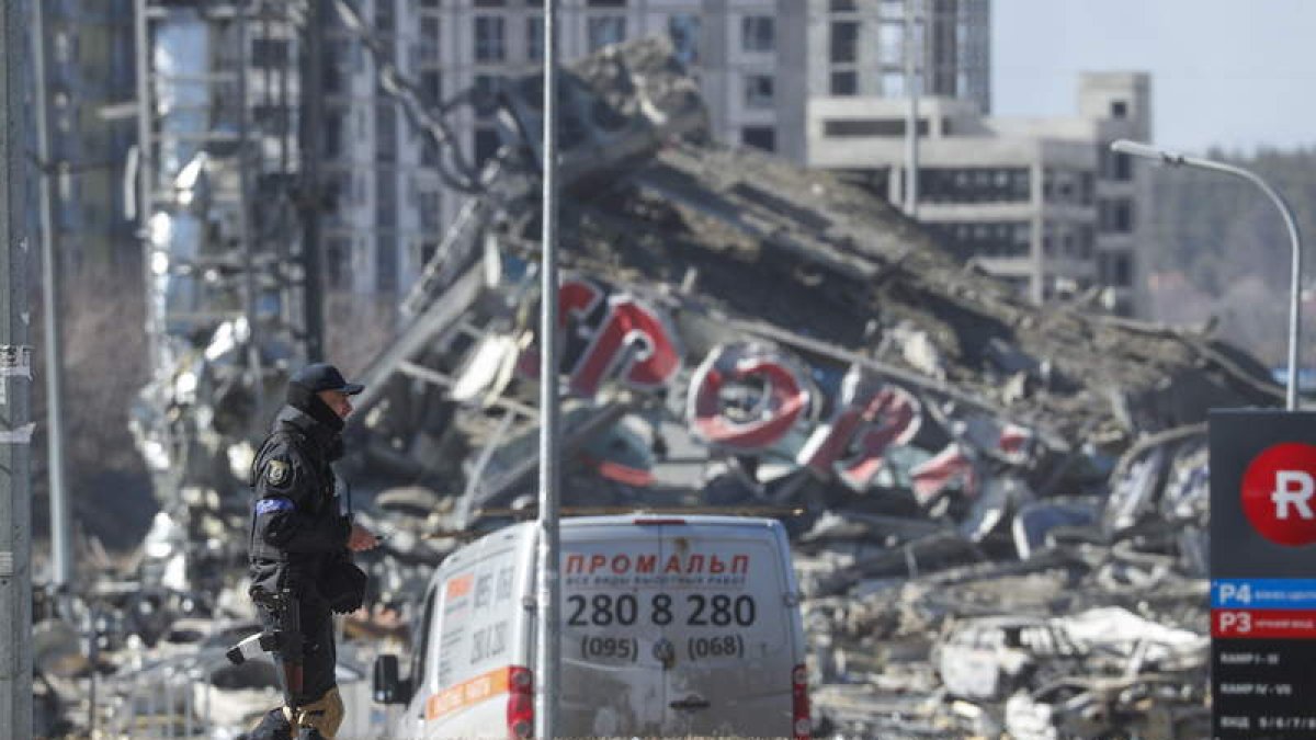 Un miembro de la defensa ucraniana pasa ante las ruinas provocadas en Kiev por el disparo de un misil ruso a un centro comercial. SERGEY DOLZHENKO