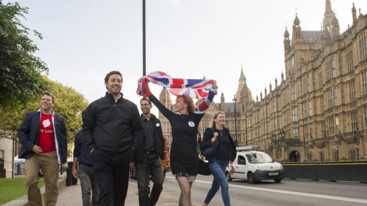 Partidarios de abandonar la UE celebran el resultado del referéndum mientras pasan frente al Parlamento, en Londres.