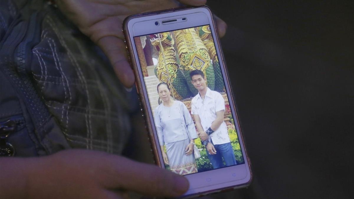 La tia de Ekapol Chanthawong muestra una foto en el móvil del entrenador en la que aparace junto a su abuela.
