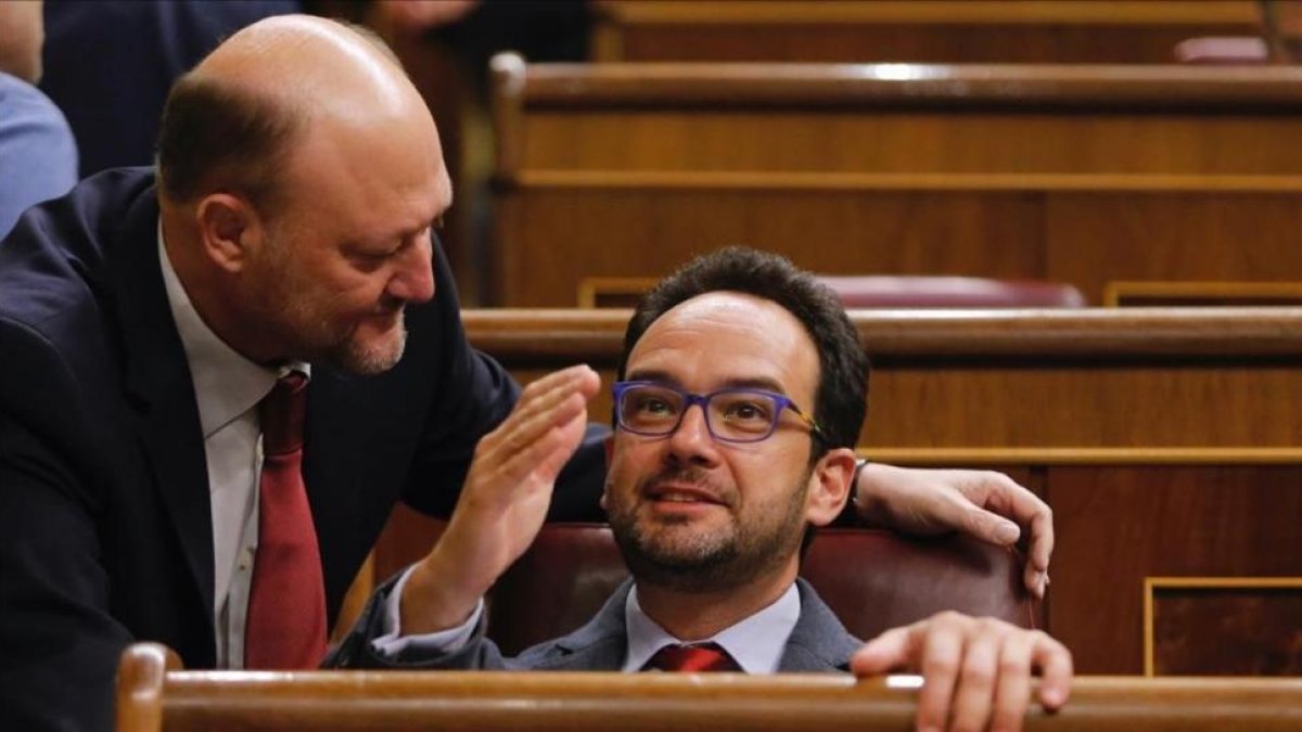 Antonio Pradas, de pie, conversa con el líder del grupo parlamentario del PSOE, Antonio Hernando, en el hemiciclo.