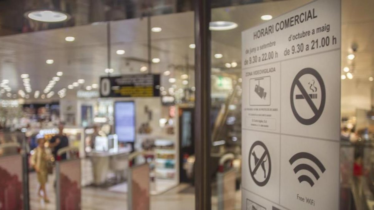 Cartel con el nuevo horario comercial en una tienda de Barcelona.