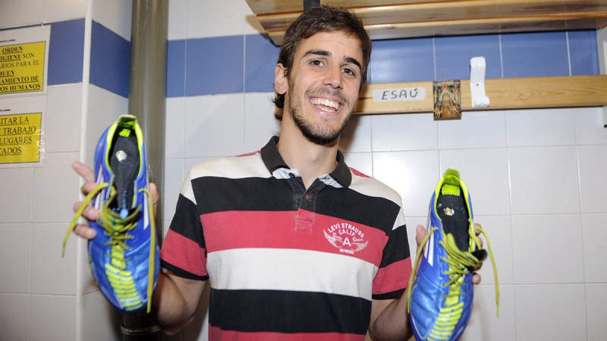 El futbolista de la Cultural Esaú García muestra las botas que utiliza cada domingo con las dos medallas de la Virgen del Camino pegadas debajo de la plantilla.