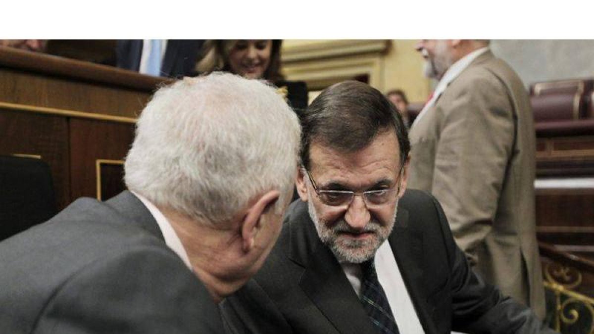 El presidente del Gobierno, Mariano Rajoy (d), conversa con el ministro de Asuntos Exteriores y de Cooperación, José Manuel García-Margallo (i), al inicio de la sesión de control al Gobierno.